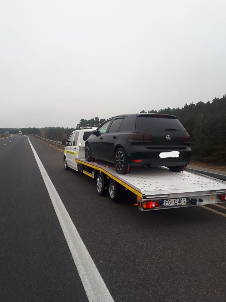 Laweta Magdeburg holująca samochód osobowy na autostradzie, profesjonalna pomoc w sytuacjach awaryjnych.